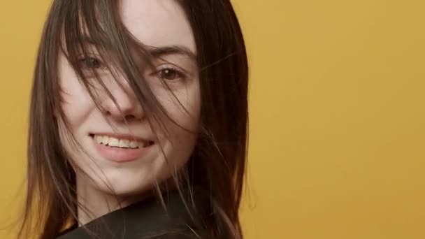 Uçan Saçlı Genç Kadın Gülümseyerek Bakıyor Mutlu Sarı Arka Planda — Stok video