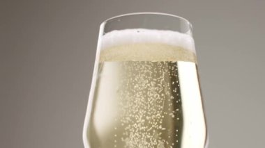 Glass of champagne on white isolated background. Champagne bubbles. Slow motion and super macro shot of tiny air bubbles flowing upwards in elegant glass of champagne on a white background