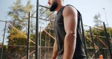 Adam dışarıda ısınmak için egzersiz yapıyor. Bacaklar için oturma egzersizleri. Sportif bir adam kalçalarının ve kalçalarının kaslarını güçlendirmek için tek bacakla hamle yapıyor. Sağlıklı yaşam tarzı ve açık hava eğitimi.