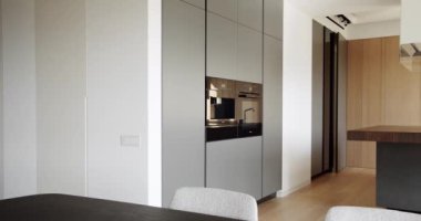 Yeni şık mobilyaları olan güzel bir mutfak. Minimalist yemek masası olan modern mutfak odası. Modern lavabosu olan yerli mutfak. Mutfak odası beyaz renklerde ve yemek alanı da doğal ahşap.