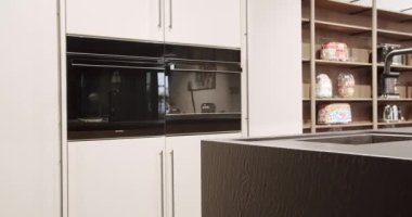 Modern beyaz ahşap mutfak mobilyası. Zarif, rahat ve Minimalist Ev. Modern siyah lavabosu olan yerli mutfak. Minimalist yemek masası olan modern mutfak odası. Modern Minimalist Ev.