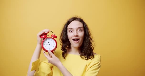 시계를 검사하는 머리에 종소리를 똑딱거리는 소리를 여성의 노란색 배경에 자명종을 — 비디오