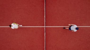 Arkadaşlar dışarıda halı kortlarında tenis oynarlar. Havadan, yukarıdan aşağıya, İHA atışı. Arkadaşlar maçtan önce el sıkışır. Rakiplerinize iyi şanslar. Arkadaşlarla aktif spor oyunu. Etkin boş zaman oyunu.