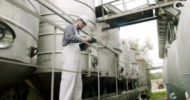 Şarap fabrikasındaki üretim ekipmanlarının kalitesini kontrol ediyor. Şarap fermantasyonu için büyük çelik fıçılar. Şarap imalatçısı şarap fabrikasında damıtma ve fermantasyon için ekipman arıyor..