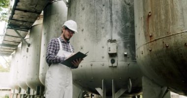 Şarap fabrikasındaki üretim ekipmanlarının kalitesini kontrol ediyor. Şarap üretim tesisi. Çelik şarap damıtma tankları. Şarap imalatçısı şarap fabrikasında damıtma ve fermantasyon için ekipman arıyor..