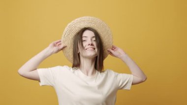 Casul Woman Smiling and she sit happy, jumps up and joy on Yellow Background in Slow Motion. emotion winner. Excitement and a fulfilled wish concept. Lucky Girl happy with hat and white T-shirt.