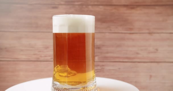 把啤酒放在大玻璃杯里 啤酒杯 啤酒杯 在一个木制的背景 近一点 旋转360度 杯子里满是啤酒 — 图库视频影像