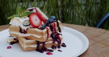Tatlı kahvaltı yemeği. Beyaz tabakta ahududu ve ev yapımı Belçika waffle 'ı. Meyveli lezzetli kahvaltı. Çilekli tam tahıllı waffle, yabanmersini, nane, çilek, yoğurt.