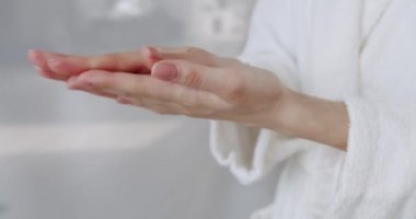 Genç ve güzel bir kadın vücut losyonu sürüyor ve cilt kremi, serum. Hyaluronik asit, yüzü olan el ve kız, cilt rutini, güzellik kremleri, elinde pipetle nemlendirici bırakan kadın..