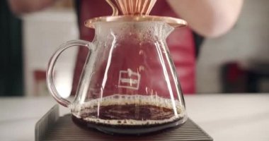 Ekin adam filtre kahve yaparken su dolduruyor. Önlüklü tanınmayan bir erkek barista modern kafede kahve hazırlarken çaydanlıktan fincana su dolduruyor. Kahve yapıyorum..