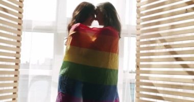 Çift, Lgbt ve lezbiyen kadınlar evde. Sarılın, gülümseyin ve bayrak sallayın. Sevgiler ve öpücükler Lezbiyen aile. Sevgi ve desteği paylaşan iki kadın el ele tutuşuyor. Yaşam tarzı ve ilişkiler.