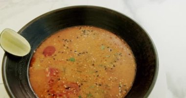 Beyaz arka planda dönen lezzetli sebze çorbası. Malzemeli sebze çorbası ve beyaz arka planda siyah tabakta limon..