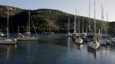 Marine port for yacht. Aerial top view of boats and yachts in marina from above. Yacht parking. Summer sea cruise on ship at green mountains island. White yacht . Sailboat. Luxury cruise trip.