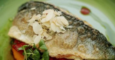 Patates püresi ve sebzeli güzel dekore edilmiş beyaz balık parçası yeşil tabakta ve beyaz arka planda dönüyor. Soslu levrek. Yakın çekim. Üst Görünüm.