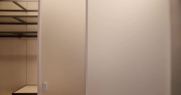 現代のミニマリストスライドドア 現代の脱衣所 透明なスライドドアは服のためのワードローブとドレッシングルームに開きます 服を着たホームワードローブ — ストック動画