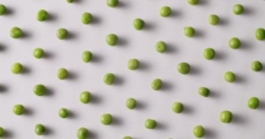 Fresh green peas placed side by side rotate on a white platform. Raw green peas in motion on isolated white background rotating with same motion.