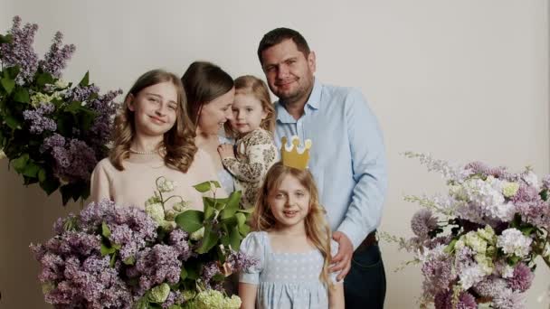 スタジオの花と白い背景に写真のための家族の肖像画立っている スローモーションで幸せな家族の肖像画 子供たちと一緒に幸せな家族 友好的な家族の概念 — ストック動画