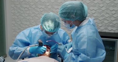 Diş hekimi, modern diş sağlığı kliniğinde hasta için diş temizliği yapıyor. Ağız temizliği ve prezervatif temizliği. Diş hijyenik diş temizliği yapan kadın hasta..