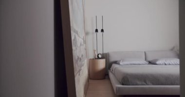 Minimalist bir dairede yatak odası, beyaz tonlarda, modern büyük resim ve siyah lamba ile. Rahat minimalist iç mekan. Şık ev, otel odası, modern mobilya, modern ev tasarımı.