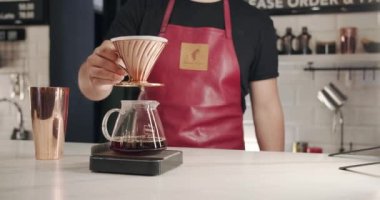 Önlüklü tanınmayan bir erkek barista modern kafede kahve hazırlarken çaydanlıktan fincana su dolduruyor. Barista kahve hazırlıyor. Ekin adam filtre kahve yaparken su dolduruyor.