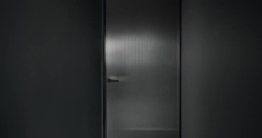 The man opens the transparent door in the modern house. modern interior design with gray colors.