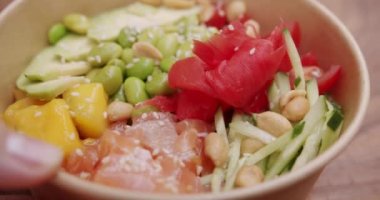 Poke kasesi, geleneksel Hawaii çiğ balık salatası. Diyet öğle yemeğinde taze balık ve sebze. Japon yemeği, somon, pirinç, avokado, edamame fasulyesi, ahşap zemin üzerinde salatalık. Çiğ yemek..
