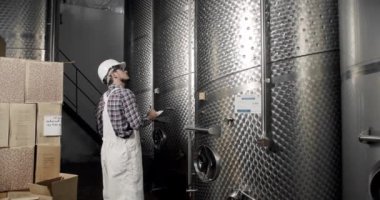 Şarap fabrikasındaki üretim ekipmanlarının kalitesini kontrol ediyor. Modern şarap imalathanesi veya şarap imalathanesi. Şarap imalatçısı şarap fabrikasında damıtma ve fermantasyon için ekipman arıyor..
