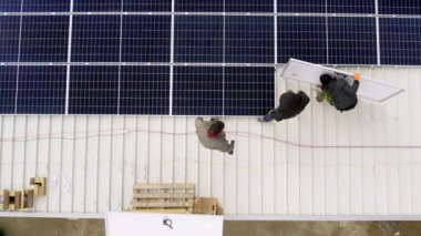 Modern güneş panelleri temiz elektrik üretir. Güneş teknisyenleri evin çatısına güneş panelleri kuruyor. Konsept. Yenilenebilir enerji, teknoloji, elektrik, hizmet, yeşil, gelecek. elektrik santrali. 