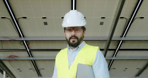 Technicien Regardant Caméra Souriant Derrière Solar Cell Farm Travers Champ — Video