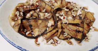 Kızarmış patlıcan. Dönen beyaz tabakta fındıklı lezzetli sebzeler. Izgara restoran yemeği. Kızarmış patlıcan. Patlıcan kızartmasının yakın çekimi..