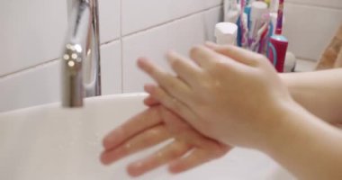 Banyoda ellerini sabunla yıkayan genç bir kadın, yakın plan. Covid 19. Coronavirus. Evdeki modern tasarım banyosunda ellerini çalkalayan biri. Hijyen. Temizlikçi Eller. Ellerimi sabunla yıkıyorum..