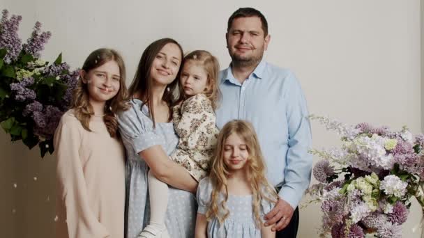 スタジオの花と白い背景に写真のための家族の肖像画立っている スローモーションで幸せな家族の肖像画 友好的な家族の概念 — ストック動画