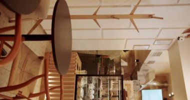 Ahşap sandalyeli, tekstil malzemeli ve siyah masalı modern minimalist kafe. Kafedeki modern ahşap kumaş sandalye ve masa mobilyası. dikey video. Boş yemek kumaşı ve tahta sandalye..