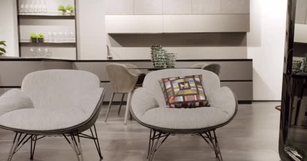 現代のミニマリストの家 現代のブラックランプ モダンなグレーと白のキッチン家具 優雅さと快適な家 暖かい居心地の良い キッチンとダイニングテーブル付きのリビングルームのファブリックモダンなグレーのアームチェア — ストック動画