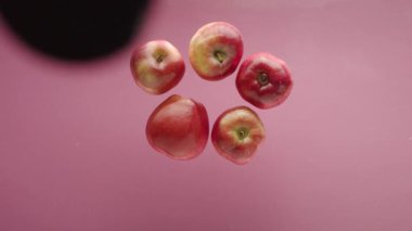 Temiz suya düşen elma. Yukarıdan, pembe arka planda, şeffaf temiz suyun ve olgun elmanın meyve yığınına düşüşünün statik görüntüsü.