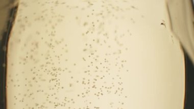 Glass of champagne on white isolated background. Champagne bubbles. Slow motion and super macro shot of tiny air bubbles flowing upwards in elegant glass of champagne on a white background