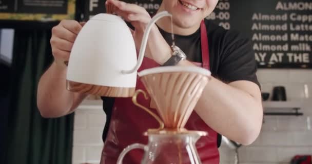 在现代咖啡店准备倒入咖啡时 在围裙中将水从水壶倒入杯中 种植难以辨认的男性咖啡师 在专业咖啡店做拿铁咖啡的咖啡店 煮咖啡 — 图库视频影像