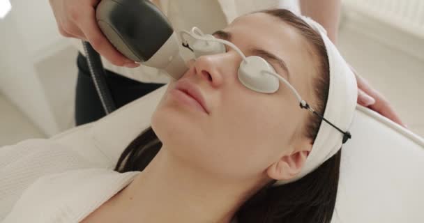 一个在医疗中心接受激光面部治疗的年轻女孩的近照 皮肤年轻化的概念 美容师美容师做分步微创手术 美容疗法 — 图库视频影像