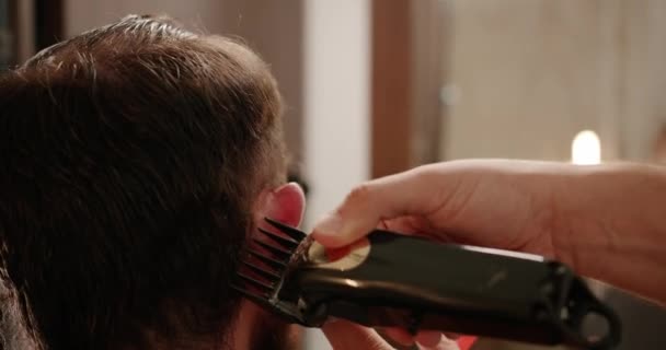 一个英俊的男人用电动理发机改头换面 近距离与修剪工作 年轻的嬉皮士白种人在现代理发店修整胡子和胡子 男人的发型 — 图库视频影像