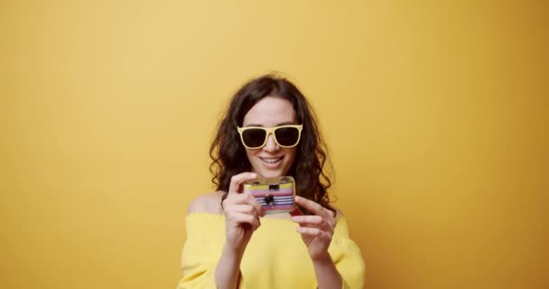 Young Girl Smiles Takes Picture Retro Camera Yellow Background She — Stock Video