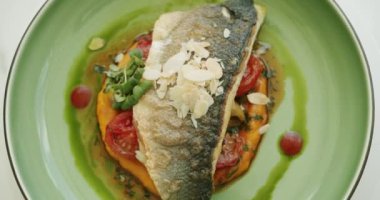 Patates püresi ve sebzeli güzel dekore edilmiş beyaz balık parçası yeşil tabakta ve beyaz arka planda dönüyor. Restoran ana yemek konsepti. Yakın çekim. Üst Görünüm.