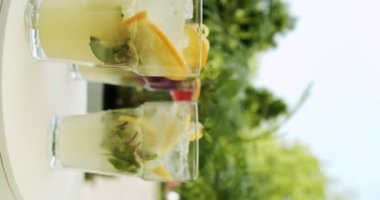 Limon, narenciye, portakal, greyfurt, nane, su ve buz ve limonata ile ferahlatıcı limonata içeceği. Gözlüklü taze limonata. Hikayeler için dikey video.