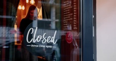 Restoran açan genç ve mutlu garson. Siyah tişörtlü neşeli sarışın kadın cam kapıyı açıyor ve sabah restoranda çalışırken gülümsüyor.