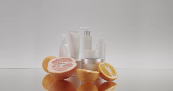 在工作室的白色背景下 白色瓶子和装有柑橘 柚子和柑橘果的管子用于化妆品 化妆品用油是以天然成分 洗涤剂 护肤为基础的 相机放大镜头 — 图库视频影像
