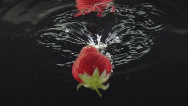 新鮮なイチゴの果物は 超スローモーションで水に落とされました 水の中で新鮮なイチゴを落下 ビーティーストロベリー水を通して 健康的な自然ビーガンフードの概念 おいしい夏のベリー — ストック動画