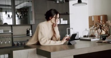 Modern mutfak odasında ve çatı katında dijital tablet kullanan güzel bir kadın. Haber, iş ve sosyal medya için dijital tableti evdeki tavan arası mutfağında çevrimiçi hale getirmek
