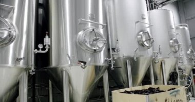 Stainless steel tanks for brewing beer. Huge stainless vats in a brewery. Equipment for beer fermentation. Brewing equipment. Factory, brewery concept. Modern brewery.