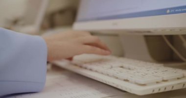 Bilgisayarda klavyede yazı yazan bir kadının yakın çekimi. Ofiste internet projesinde çalışan, internetten bilgi arayan ve iş arkadaşlarıyla sohbet eden bir kadın..
