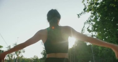 Sportif kadın esmer, dışarıda egzersiz yapan, ısınan ve kollarını esneten biri. Genç bir bayanın güneşli bir sabahta doğada fitness eğitimi var. Sağlıklı yaşam tarzı kavramı