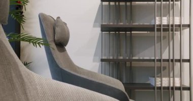 Köşedeki kanepe, sandalye ve kitaplığı olan lüks modern ev içi. Moda mobilyalar. Minimalist İç İşleri. Samimi Modern Mobilya Tasarımı. Lüks Zarif Oda. Gayrimenkul özel evi.